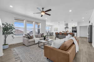 Living room featuring light hardwood / wood-style floors, a mountain view, and ceiling fan with notable chandelier