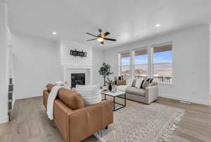 Living room featuring ceiling fan, light hardwood / wood-style flooring, and a fireplace