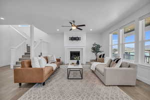 Living room with a brick fireplace, light hardwood / wood-style floors, and ceiling fan