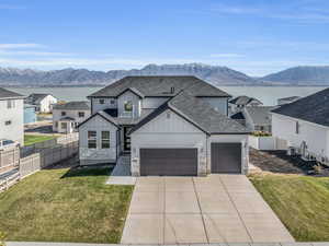 View of front of property featuring a mountain view, central AC, a garage, and a front lawn