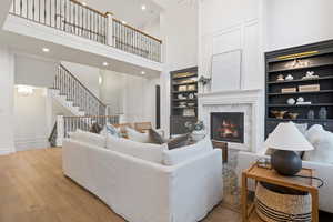 Living room featuring built in features, light wood-type flooring, and a towering ceiling