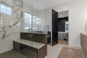 Bathroom with a wealth of natural light, tile patterned flooring, vanity, and walk in shower