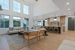 Living room featuring light hardwood / wood-style floors, a high ceiling, and an inviting chandelier