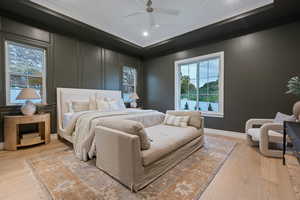 Bedroom with ceiling fan, light wood-type flooring, and multiple windows