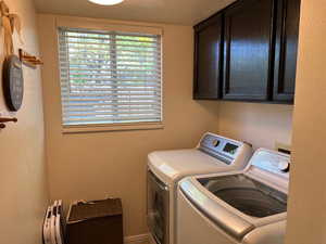 Laundry room featuring washer and clothes dryer and cabinets