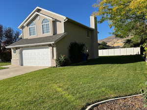 View of side of property featuring a mountain view, a garage, and a lawn