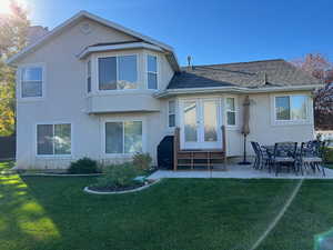 Rear view of property with a patio and a lawn