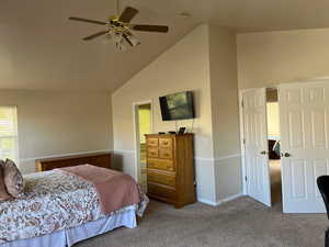 Carpeted bedroom with vaulted ceiling and ceiling fan