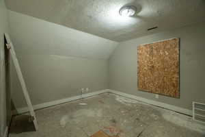 Additional living space with lofted ceiling and a textured ceiling