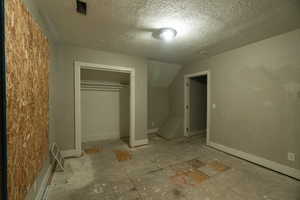 Unfurnished bedroom with a closet, a textured ceiling, and vaulted ceiling