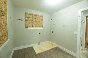 Washroom featuring a textured ceiling, hardwood / wood-style flooring, hookup for a washing machine, hookup for a gas dryer, and hookup for an electric dryer