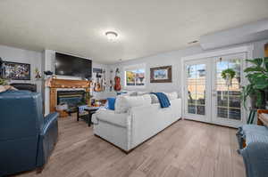 Living room with french doors, a textured ceiling, and light wood-type flooring