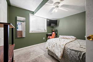 Carpeted bedroom featuring a textured ceiling and ceiling fan