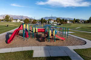 View of playground featuring a mountain view and a lawn