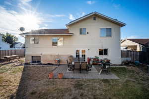 Back of property with a patio area, a trampoline, and a lawn