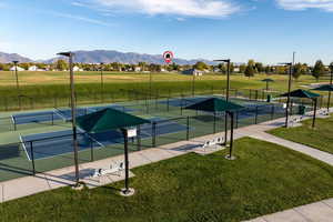 View of community with a yard, a mountain view, and tennis court