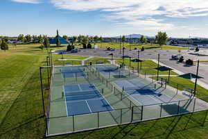 View of tennis court with a mountain view and a lawn