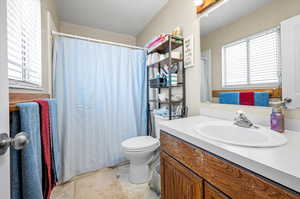 Bathroom featuring toilet, tile patterned flooring, curtained shower, vanity, and a textured ceiling