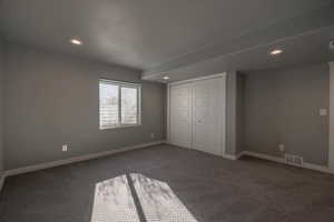 Unfurnished bedroom with dark carpet and a closet