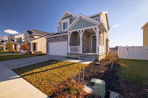 View of front facade featuring a garage, covered porch, and a front lawn