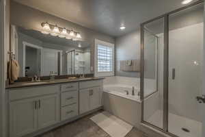 Bathroom featuring tile patterned floors, vanity, plus walk in shower, and a textured ceiling