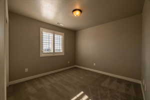 Carpeted spare room featuring a textured ceiling