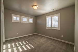 Empty room with carpet and a textured ceiling