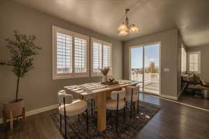 Dining space featuring dark wood-type flooring, a healthy amount of sunlight, and a notable chandelier