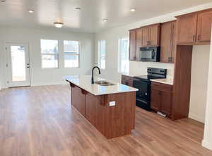 Kitchen with a center island with sink, sink, black appliances, and plenty of natural light