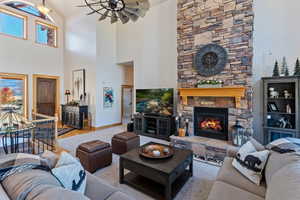 Living room featuring a stone fireplace, high vaulted ceiling, and light hardwood / wood-style floors