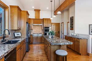 Kitchen with appliances with stainless steel finishes, sink, a kitchen island, backsplash, and light hardwood / wood-style floors