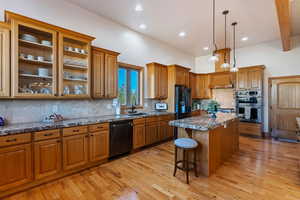 Kitchen featuring tasteful backsplash, black appliances, sink, a center island, and light hardwood / wood-style flooring