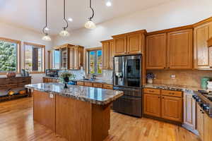 Kitchen with stone counters, appliances with stainless steel finishes, pendant lighting, and light hardwood / wood-style floors