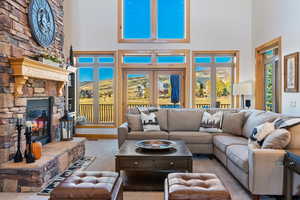 Living room with a high ceiling, light carpet, a fireplace, and plenty of natural light