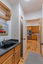 Laundry room currently set up as a coffee nook featuring light hardwood / wood-style floors and sink