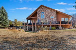 Back of house with a deck and a lawn