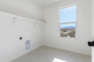 Laundry room with window, electric dryer hookup, and upper shelving