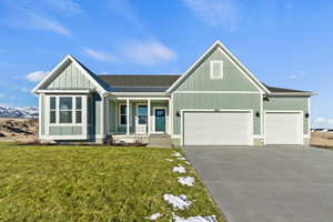 View of front of house with a front yard, a garage, and covered porch