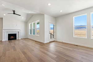 Grand living room with a fireplace, mantle, vaulted ceilings, ceiling fan, and entry to the backyard deck