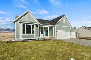 View of front of property featuring covered porch, a front lawn, and a garage
