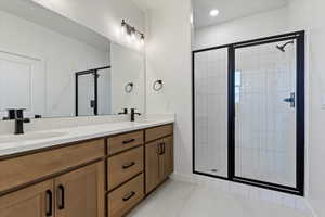 Primary bathroom with a walk-in shower, double vanity, and tiled floors