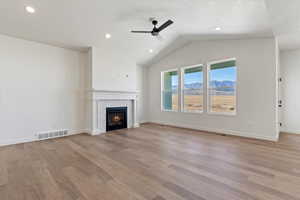Grand living room with a fireplace, mantle, vaulted ceilings, and ceiling fan