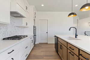 Gourmet kitchen with GE Cafe gas stove, double ovens, dishwasher, a wood hood, and enlarged island