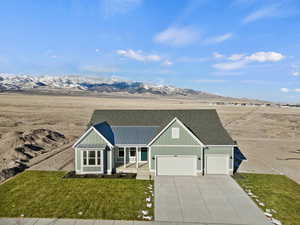 Single story home featuring covered porch, a front yard, a garage, and a mountain view