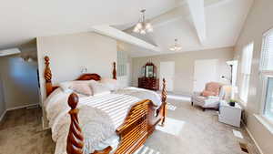 Carpeted bedroom with an inviting chandelier and lofted ceiling with beams