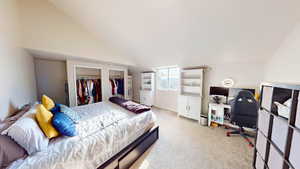 Bedroom featuring lofted ceiling and light colored carpet