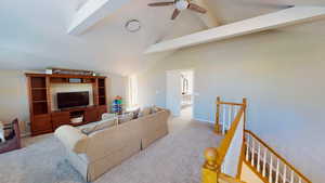 Carpeted living room with ceiling fan and vaulted ceiling with beams