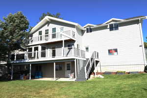 Back of property featuring a yard, a deck, and a patio area