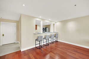 Living/dining area with bar top seating arrangement.  Large welcoming entryway to condo.  Hardwood flooring, new paint.