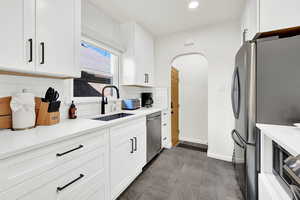 Kitchen featuring white cabinetry, stainless steel appliances, decorative backsplash, and sink